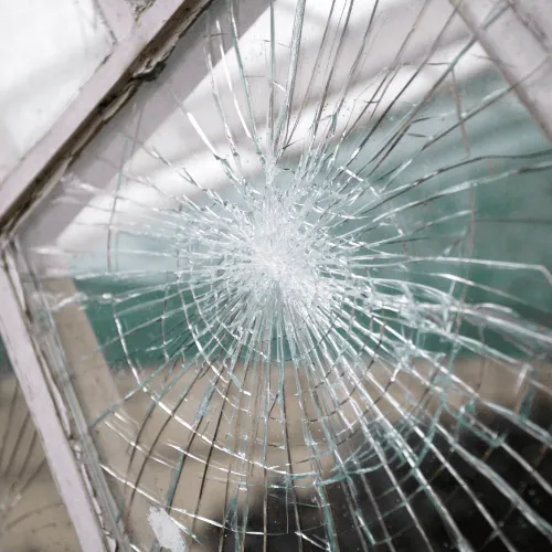 Broken glass pane with intricate cracks following impact - Tanic can replace your window glass.