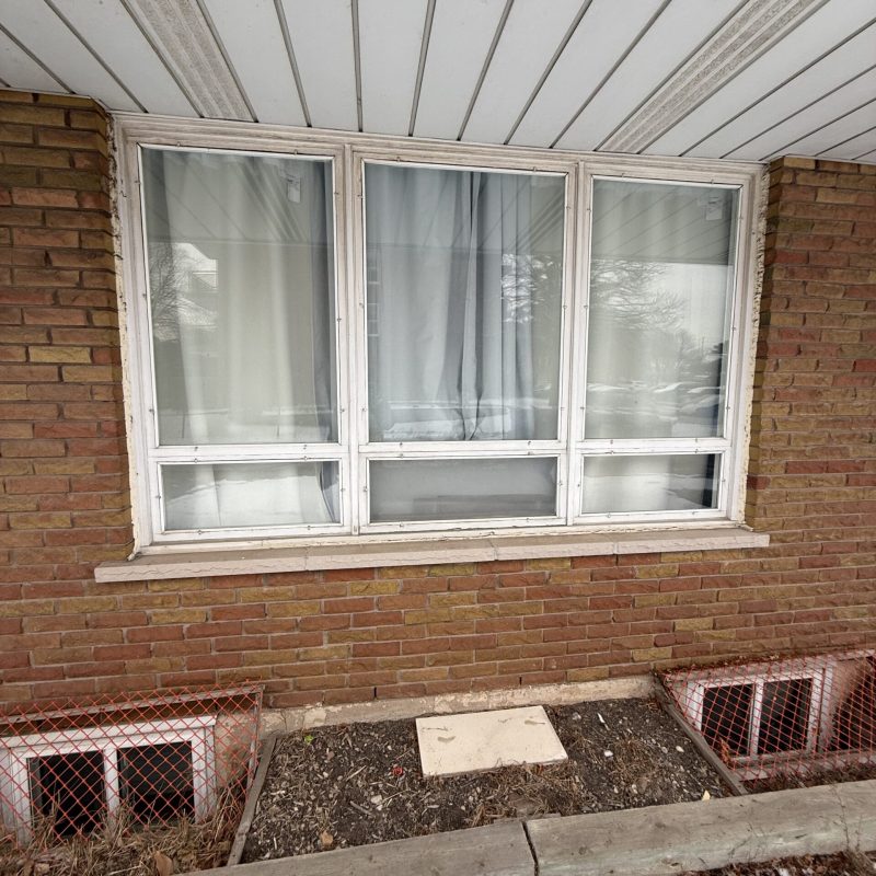Large residential picture window with deteriorating white frames.